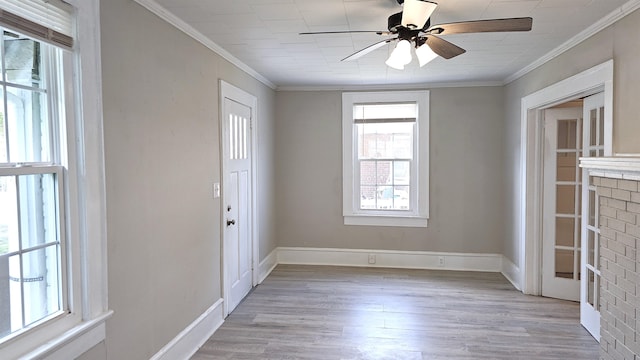 foyer entrance featuring ceiling fan, a brick fireplace, light wood-type flooring, and crown molding