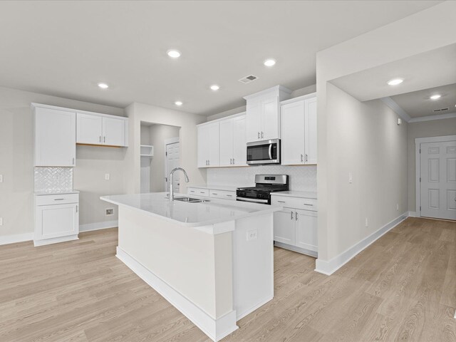 kitchen featuring white cabinets, sink, appliances with stainless steel finishes, and an island with sink