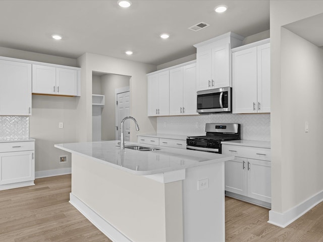 kitchen featuring white cabinets, appliances with stainless steel finishes, a kitchen island with sink, and sink