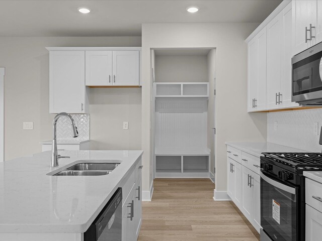 kitchen with light stone countertops, stainless steel appliances, sink, light hardwood / wood-style floors, and white cabinetry