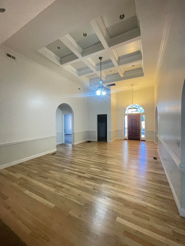 unfurnished living room with ceiling fan, coffered ceiling, beamed ceiling, hardwood / wood-style flooring, and ornamental molding