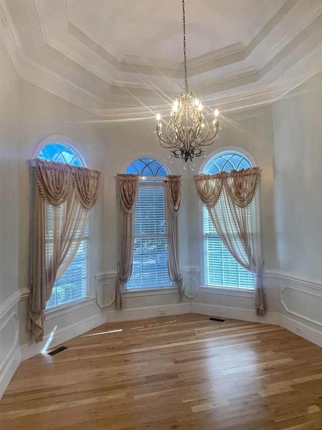 unfurnished dining area with a tray ceiling, hardwood / wood-style flooring, ornamental molding, and a wealth of natural light