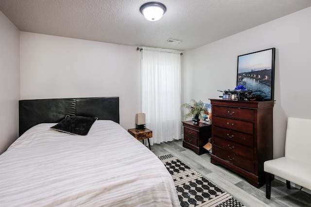 bedroom with light hardwood / wood-style floors and a textured ceiling