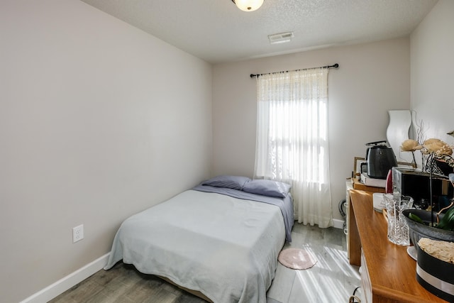 bedroom with wood-type flooring and a textured ceiling