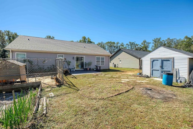 rear view of house with a storage unit, a yard, and a patio area