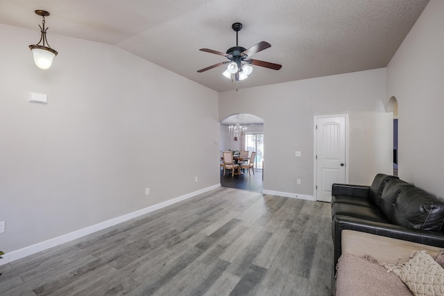 unfurnished living room with ceiling fan, hardwood / wood-style flooring, a textured ceiling, and lofted ceiling