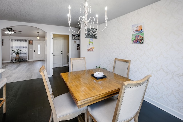 dining room with hardwood / wood-style flooring, a textured ceiling, and ceiling fan with notable chandelier