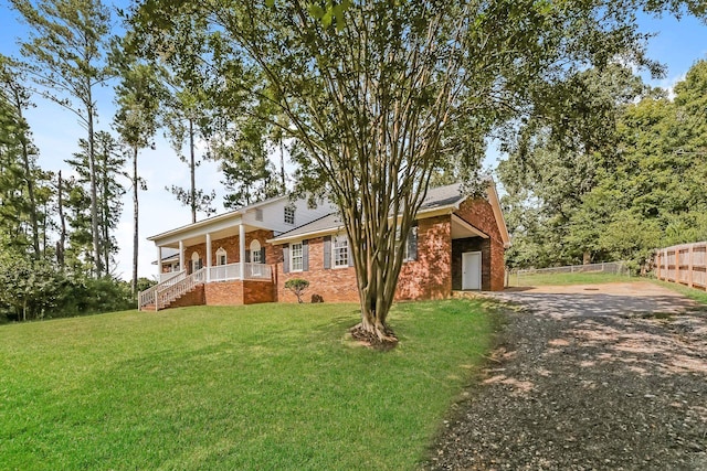 view of front of property featuring covered porch, a garage, and a front lawn