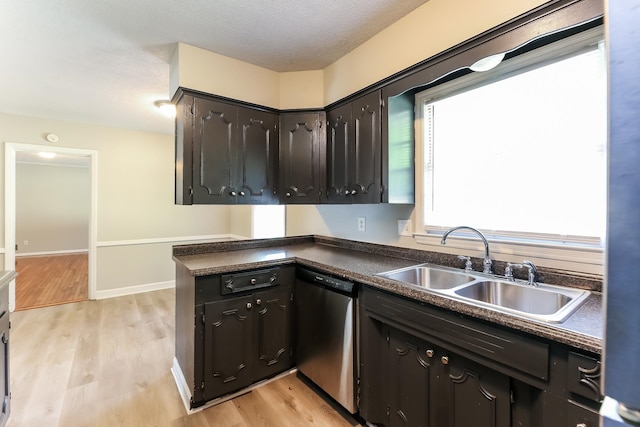 kitchen with light hardwood / wood-style floors, a textured ceiling, stainless steel dishwasher, and sink