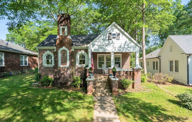 tudor home featuring covered porch and a front lawn