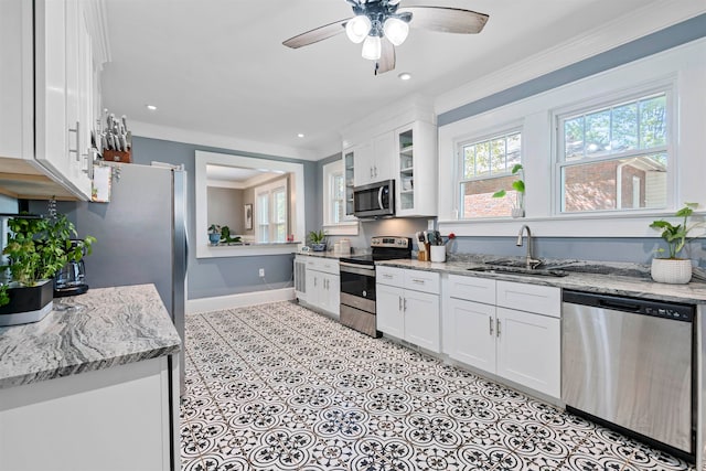 kitchen with appliances with stainless steel finishes, crown molding, white cabinetry, and light stone counters