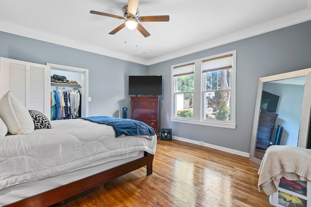 bedroom featuring ceiling fan, hardwood / wood-style flooring, crown molding, a closet, and a walk in closet