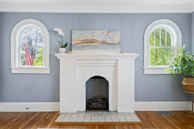 details featuring hardwood / wood-style flooring, ornamental molding, and a brick fireplace