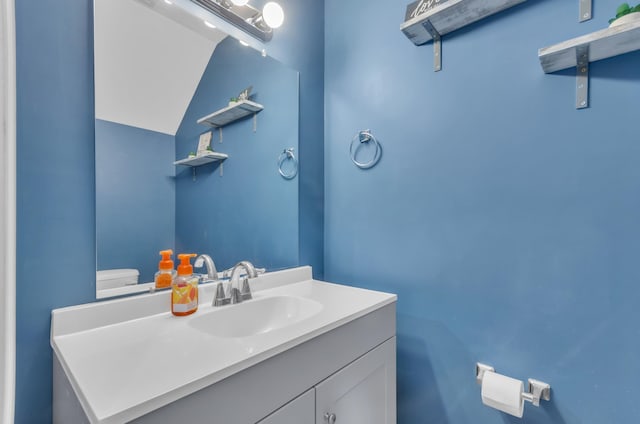 bathroom featuring vanity, vaulted ceiling, and toilet