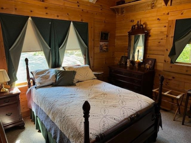 bedroom featuring carpet flooring and wooden walls