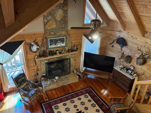 living room featuring a stone fireplace, lofted ceiling with beams, hardwood / wood-style floors, wooden walls, and wood ceiling