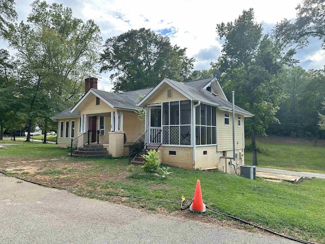 view of front of home with a sunroom and a front yard