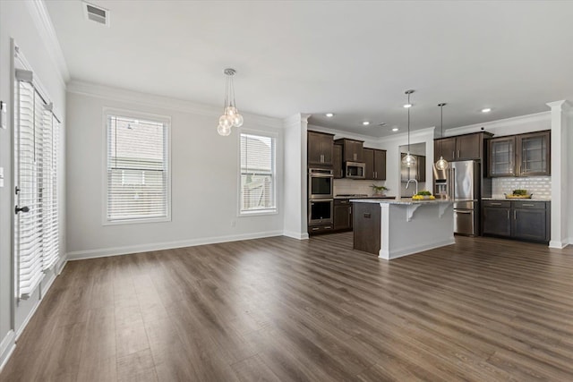 kitchen featuring appliances with stainless steel finishes, a kitchen breakfast bar, an island with sink, and pendant lighting