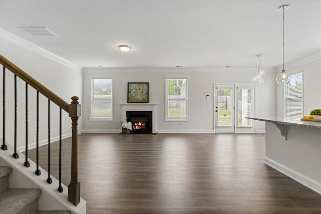 unfurnished living room with ornamental molding, dark wood-type flooring, and a chandelier