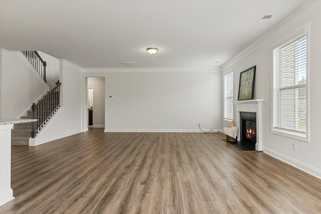 unfurnished living room with crown molding, hardwood / wood-style flooring, and a wealth of natural light