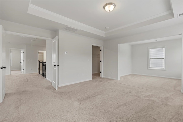 spare room featuring light carpet, crown molding, and a raised ceiling