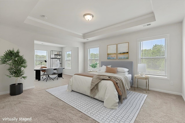 bedroom with light carpet, multiple windows, and a tray ceiling