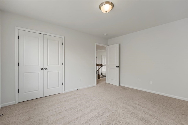 unfurnished bedroom featuring light carpet and a closet