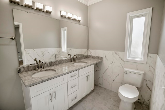 bathroom with toilet, tile patterned floors, tile walls, vanity, and ornamental molding