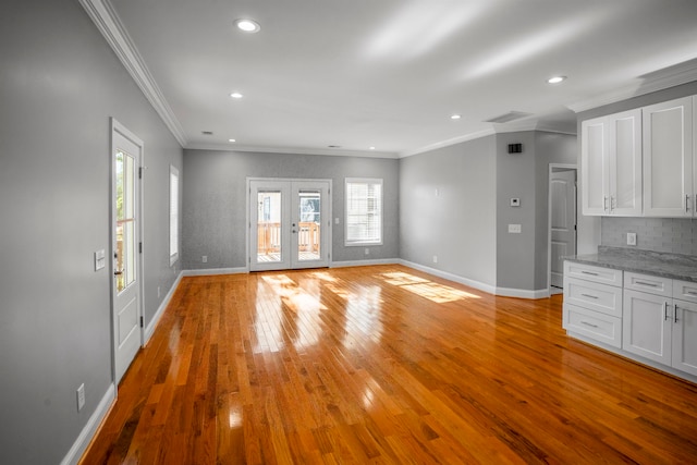 unfurnished living room featuring crown molding, light hardwood / wood-style floors, and french doors