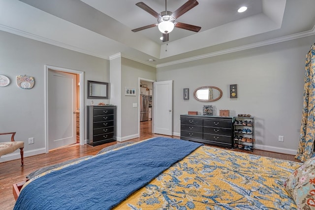 bedroom featuring stainless steel fridge, a raised ceiling, ceiling fan, wood-type flooring, and crown molding