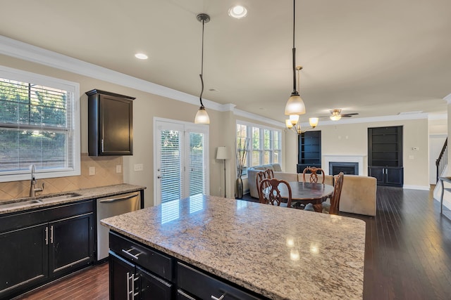 kitchen with crown molding, light stone countertops, sink, and hanging light fixtures