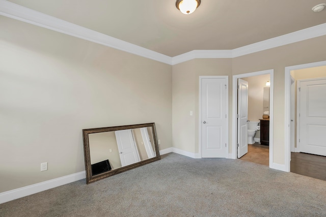 unfurnished bedroom featuring carpet, crown molding, and ensuite bathroom