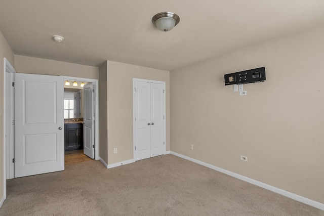 unfurnished bedroom featuring light carpet, a closet, and ensuite bathroom