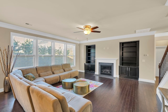 living room with a wealth of natural light, ornamental molding, dark wood-type flooring, and built in features