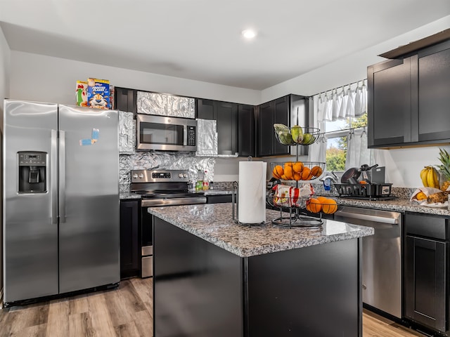 kitchen featuring light stone countertops, a kitchen island, appliances with stainless steel finishes, and light hardwood / wood-style flooring