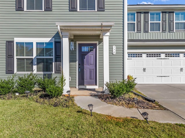 property entrance featuring a garage and a lawn