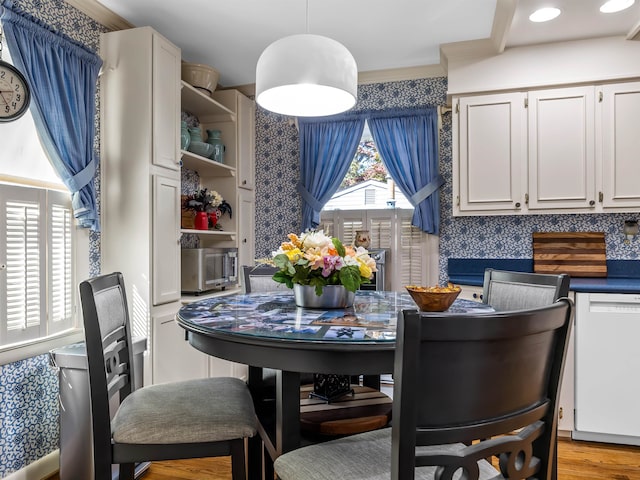 dining space with ornamental molding and light hardwood / wood-style flooring