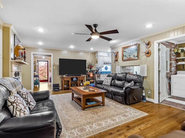 living room featuring hardwood / wood-style floors, ceiling fan, crown molding, and washer / clothes dryer