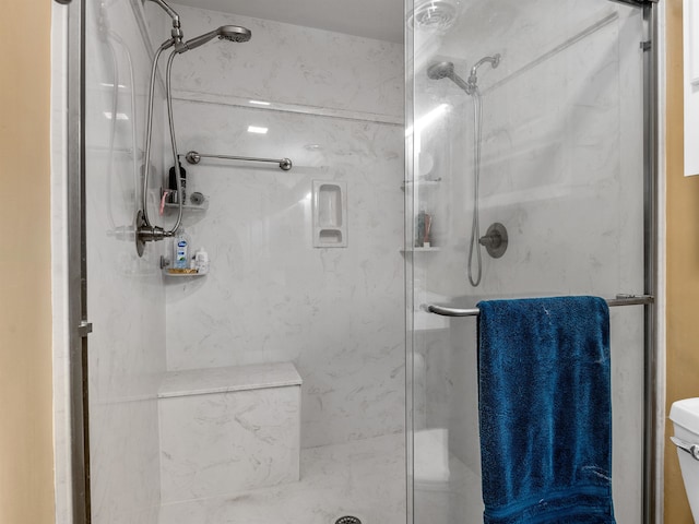 bathroom featuring a shower with shower door and toilet