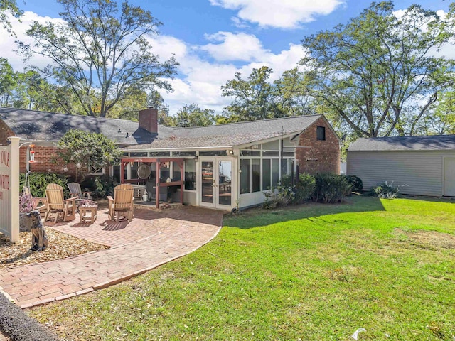 rear view of house featuring a patio area, a lawn, and a sunroom