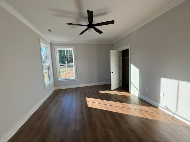 empty room with crown molding, dark wood-type flooring, and ceiling fan