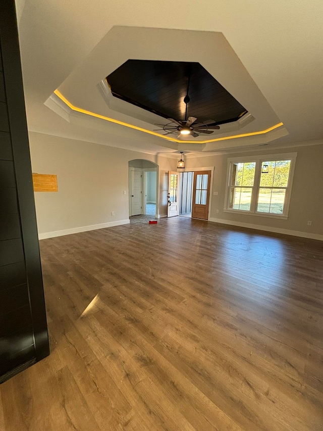 unfurnished living room featuring a tray ceiling, wood-type flooring, and ceiling fan