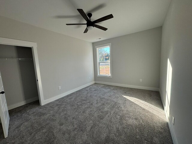 unfurnished bedroom featuring dark carpet, a closet, and ceiling fan