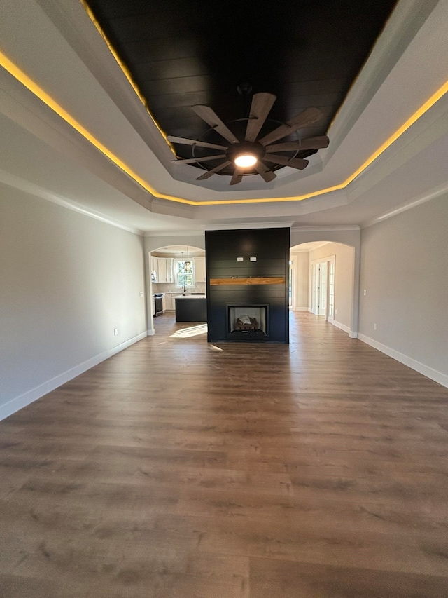 unfurnished living room featuring dark hardwood / wood-style flooring, a raised ceiling, and ceiling fan