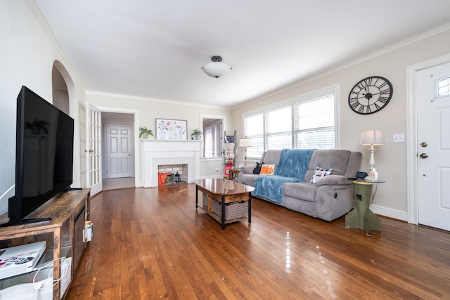 living room with crown molding, a tile fireplace, and dark hardwood / wood-style flooring