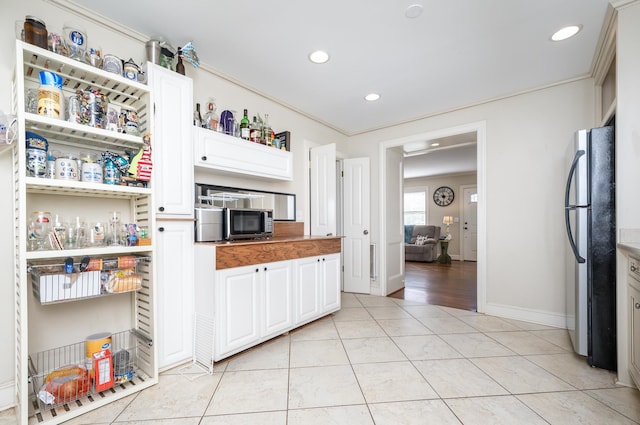 kitchen with butcher block counters, appliances with stainless steel finishes, light tile patterned floors, and white cabinets