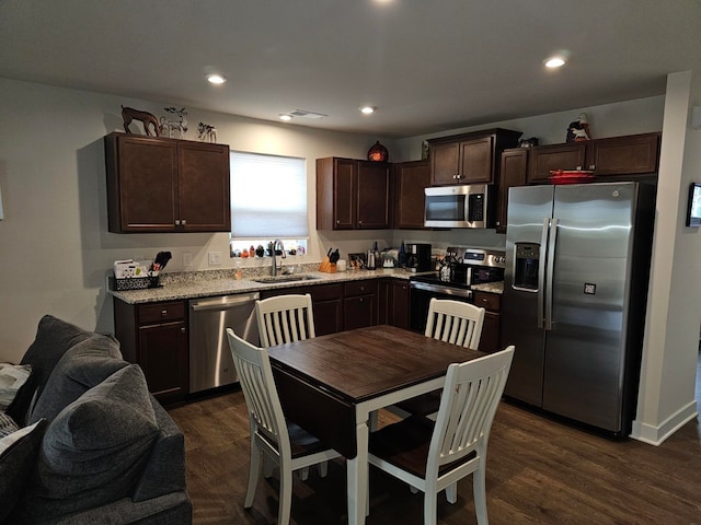 kitchen with dark brown cabinets, stainless steel appliances, dark wood-type flooring, and sink