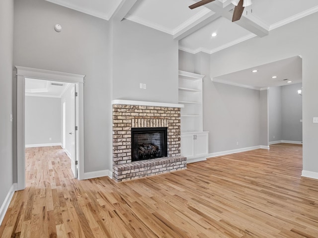 unfurnished living room featuring beam ceiling, ornamental molding, light hardwood / wood-style flooring, and a brick fireplace