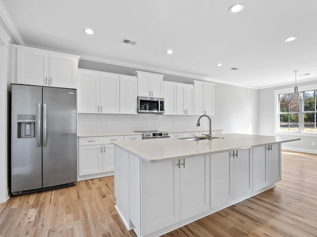 kitchen featuring a center island with sink, ornamental molding, sink, white cabinets, and appliances with stainless steel finishes