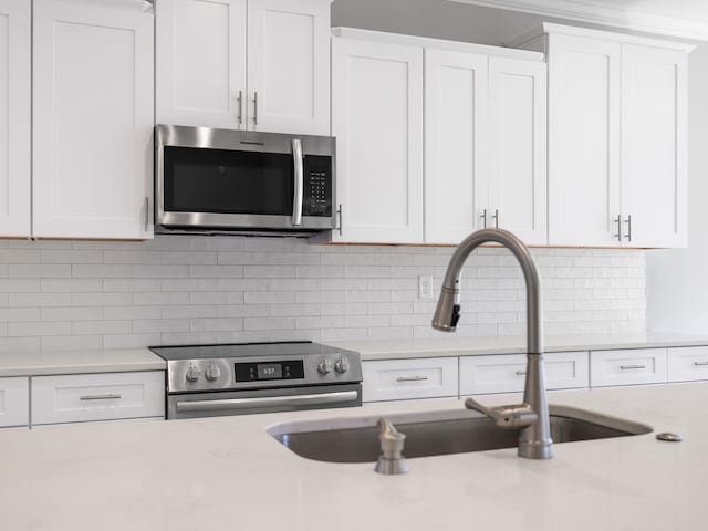 kitchen with backsplash, appliances with stainless steel finishes, and white cabinets